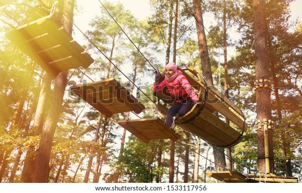 Happy child climbing in the trees. Rope park.\
Adventure climbing. Rope\
bridges.