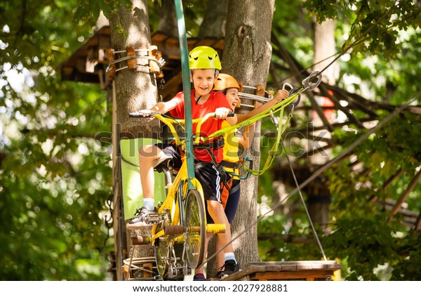Happy child climbing in the\
trees. Rope park. Climber child. Early childhood development.\
Roping park. Balance beam and rope bridges. Rope park - climbing\
center