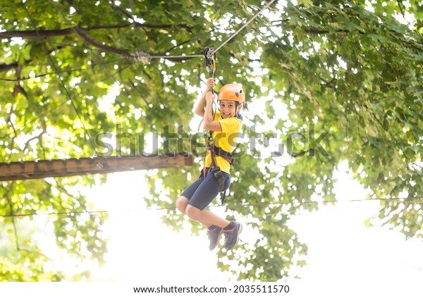 Happy child climbing in the\
trees. Rope park. Climber child. Early childhood development.\
Roping park. Balance beam and rope bridges. Rope park - climbing\
center