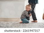 Happy, child clinging to leg of woman and playful fun and smile on carpet in home with mother. Little girl playing, laughing and joking with happiness, mom in pajamas and trust on floor in apartment.