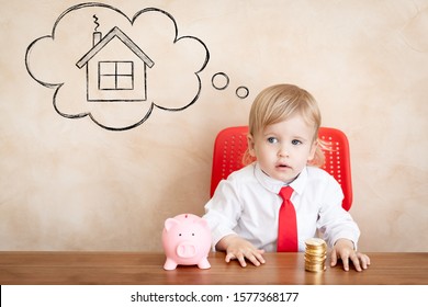 Happy child with coins and piggy bank. Funny kid playing at home. Real estate, investment and new home concept