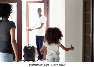 Happy Child Daughter Running To Meet African Dad Coming Home With Suitcase, Rear View At Little Kid Girl Hurrying To Hug Father Arriving After Business Trip, Welcome Back Daddy, Black Family Reunion