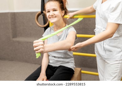 Happy Child With Disability Does Physical Exercises With Support Of Doctor In Rehabilitation Room. Kid With Special Needs. Rehabilitation. Cerebral Palsy. Motor Disorder. Horizontal plane