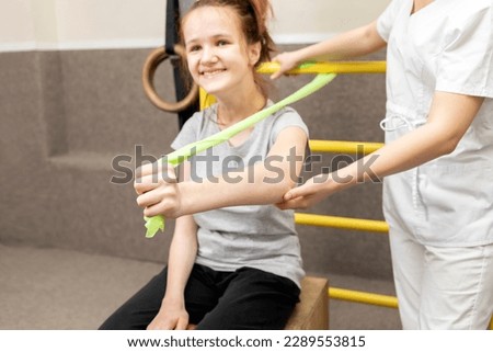 Happy Child With Disability Does Physical Exercises With Support Of Doctor In Rehabilitation Room. Kid With Special Needs. Rehabilitation. Cerebral Palsy. Motor Disorder. Horizontal plane
