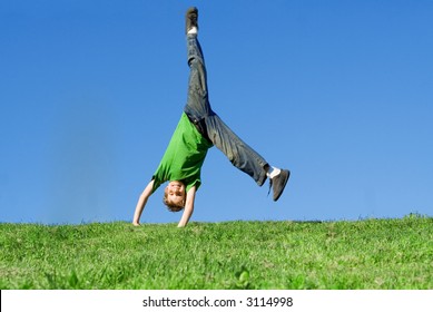 Happy Child Doing Cartwheel On Hill