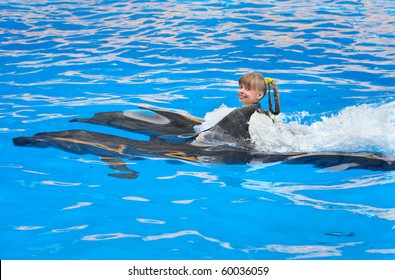 Happy child and dolphin swimming in blue water.