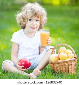 Happy Child Drinking Apple Juice In Spring Park