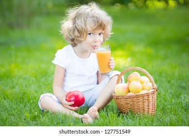 Happy Child Drinking Apple Juice In Spring Park