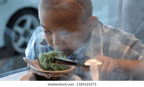 Happy Child Eating Delicious Noodle In Restaurant. Asian Boys Who Have Vision Disabilities. Left Eye Is Not Visible From Brain Surgery. Come Back To Normal Life Effect Of The Treatment. New Life