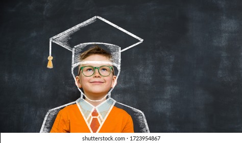 Happy child in education cap against chalkboard. School boy in green glasses and orange uniform.  - Powered by Shutterstock