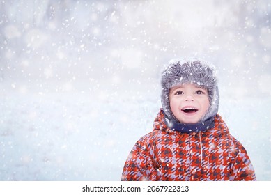 Happy Child Enjoying Winter Snowy Day. Three Years Old Cute Smiling Trendy Hipster Boy In Winter Wear (clothes). Kid Playing Outside. Winter, Healthy Lifestyle, Christmas Concept. Selective Focus.
