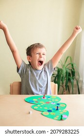 Happy Child Enjoys Victory In The Board Game. Board Game In Form Of Christmas Tree. Concept Of Spending Time With Family