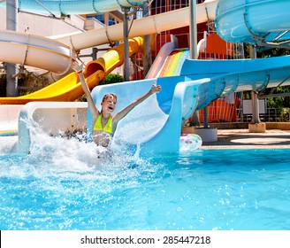 Happy child girl in bikini sliding water park.