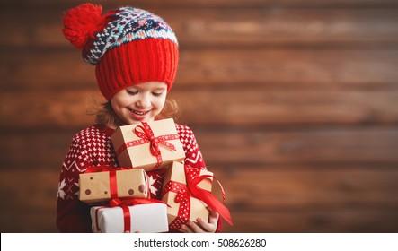 Happy Child Girl With A Christmas Present On Wooden Background