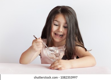 Happy Child Girl Eating Ice Cream In White And Chocolate Bowl On White Background. Enjoying Delicious.