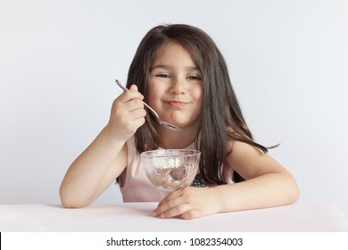 Happy Child Girl Eating Ice Cream In White And Chocolate Bowl On White Background. Enjoying Delicious.