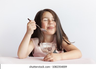 Happy Child Girl Eating Ice Cream In White And Chocolate Bowl On White Background. Enjoying Delicious.