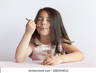 Happy Child Girl Eating Ice Cream In White And Chocolate Bowl On White Background. Enjoying Delicious.