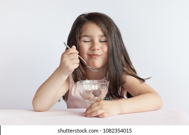 Happy Child Girl Eating Ice Cream In White And Chocolate Bowl On White Background. Enjoying Delicious.