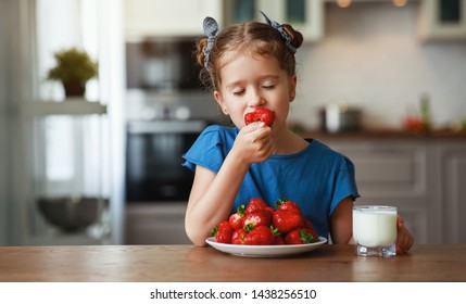 happy child girl eating strawberries with milk at home
 - Powered by Shutterstock