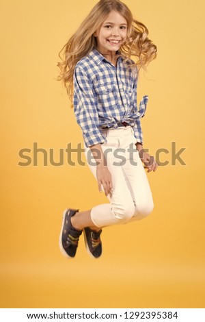 Happy child girl jumping on orange background