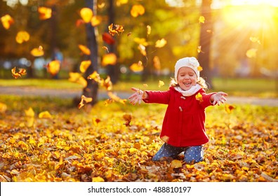 happy child girl laughing and playing  leaves in autumn outdoors