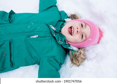 Happy Child Girl Lying On The Snow And Making A Snow Angel