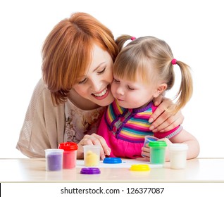 Happy Child Girl And Mother Sitting At Table And Playing With Colorful Clay Toy