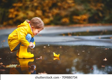 happy child girl with paper boat in a puddle in   autumn on nature