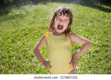 Happy Child Girl Playing With Garden Hose And Having Fun With Spray Of Water In Sunny Backyard. Summer Time. Kid Boy Helps Water Garden With Hose. Slow Life. Enjoying The Little Things. Summer Holiday