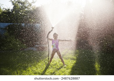 Happy child girl playing with garden hose and having fun with spray of water in sunny backyard. Summer time. Kid girl  helps water garden with hose. Enjoying the little things. Summer holiday - Powered by Shutterstock