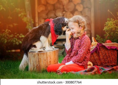 happy child girl playing and having fun with her cavalier king charles spaniel dog in autumn sunny garden