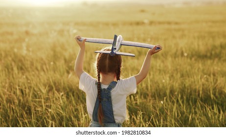 Happy Child, Girl Playing With Toy Airplane On Summer Field. Kid Runs On Grass With A Toy Smolot. Happy Family Is Playing In Park. Little Daughter Dreams Of Flying. Carefree Kid Playing Outdoors