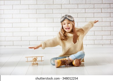 Happy Child Girl Playing With Toy Airplane. The Dream Of Becoming A Pilot