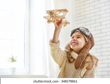 Happy Child Girl Playing With Toy Airplane. The Dream Of Becoming A Pilot