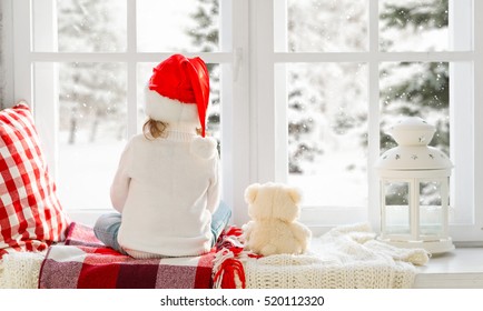 Happy Child Girl Sitting Back In The Winter Window Christmas