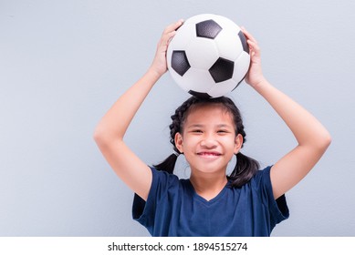 Happy child girl smiling to camera with a football on her head