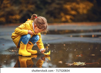 happy child girl with umbrella and paper boat in a puddle in   autumn on nature - Powered by Shutterstock