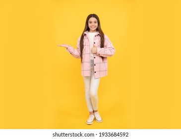 happy child girl wear pink checkered shirt presenting product, copy space, sale.