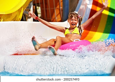 Happy child girl in yellow bikini sliding water park.