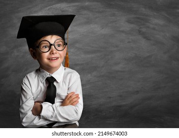 Happy Child in Glasses and Graduation Hat thinking over Blackboard. Cheerful smiling Preschool Boy in Eyeglasses over Chalkboard. Clever Kids Elementary Education