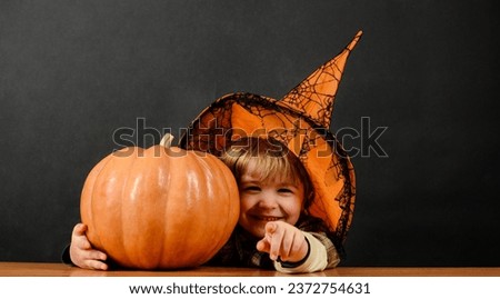 Happy child in Halloween costume with magic pumpkin. Kids trick or treat. Little boy in witch hat with jack-o-lantern. Preparation for Halloween holiday. Traditional food. Halloween sales. Discount.