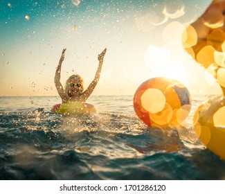 Fröhliches Kind, das sich in den Sommerferien amüsiert. Kinder, die mit Gummiente und Ball im Meer spielen.  Gesunder Lebensstil Frühlingspause!