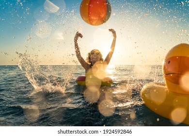 Happy Child Having Fun On Summer Vacation. Kid Playing With Rubber Duck And Ball In The Sea. Healthy Lifestyle Concept. Spring Break!