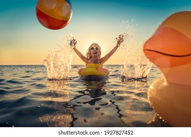 Fröhliches Kind, das sich in den Sommerferien amüsiert. Kinder, die mit Gummiente und Ball im Meer spielen. Gesunder Lebensstil Frühlingspause!