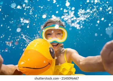 Happy child having fun on summer vacation. Funny kid jumping in swimming pool. Low angle view portrait of girl against water splash. Spring break! - Shutterstock ID 2145096467