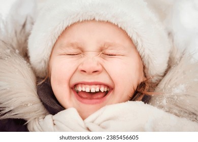 Happy Child Having Fun Smiling Lying on Snow in Winter.  Happy Laughing Emotional Kid Face in Winter Clothes Close up. - Powered by Shutterstock