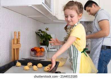 happy child help to father in kitchen. kid cooking food with dad. little girl, man in apron making dough, baking pie, cookies, making biscuit. family together home at stove, oven
