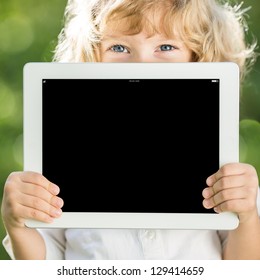 Happy Child Holding Tablet PC Outdoors In Spring Park
