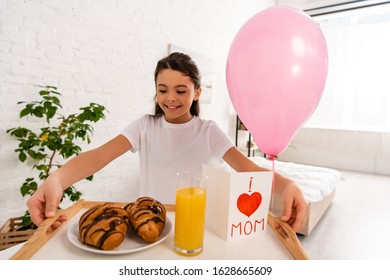 Happy Child Holding Tray With Croissants, Orange Juice And Mothers Day Card With Heart Symbol And Mom Lettering